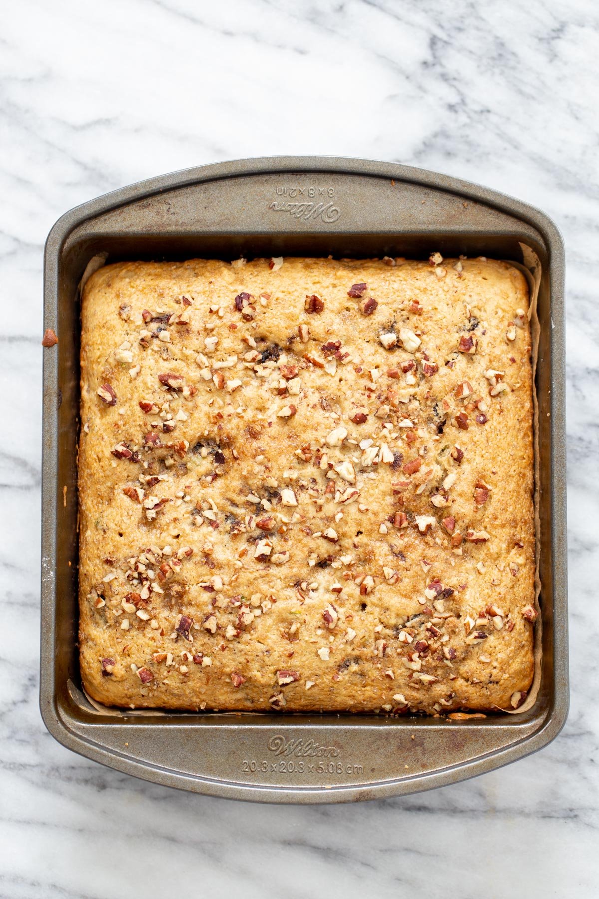 date nut cake overhead shot of a vegan date nut cake in a cake pan on a marble countertop