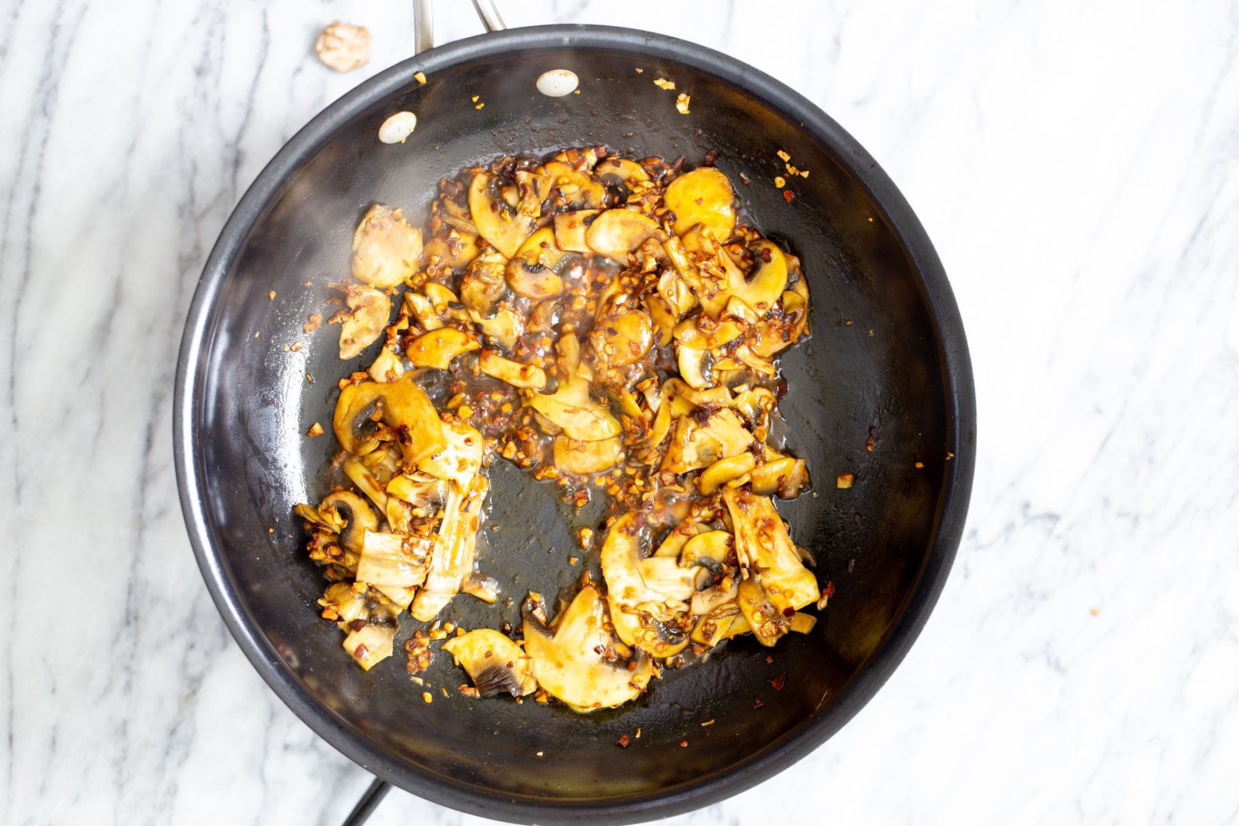 vegan garlic pasta sauteed garlic and mushrooms in a frying pan