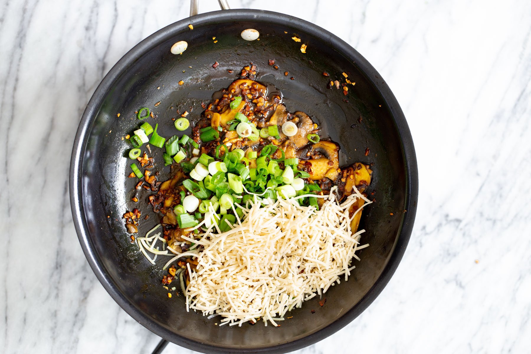 garlic, mushrooms scallions and vegan parmesan cheese in a pan