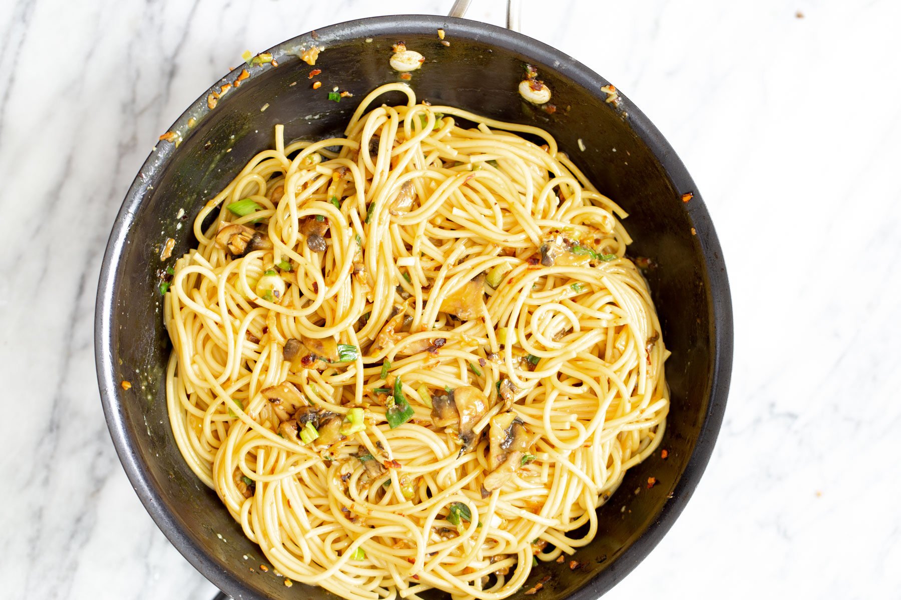 vegan garlic pasta vegan garlic pasta being tossed with pasta water in a sauteeing pan