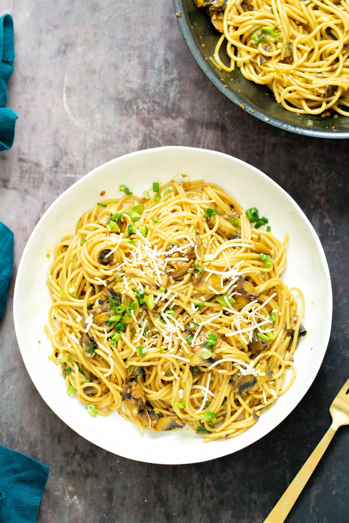 vegan garlic pasta a plate with vegan garlic pasta topped with chopped green onions and grated parmesan cheese