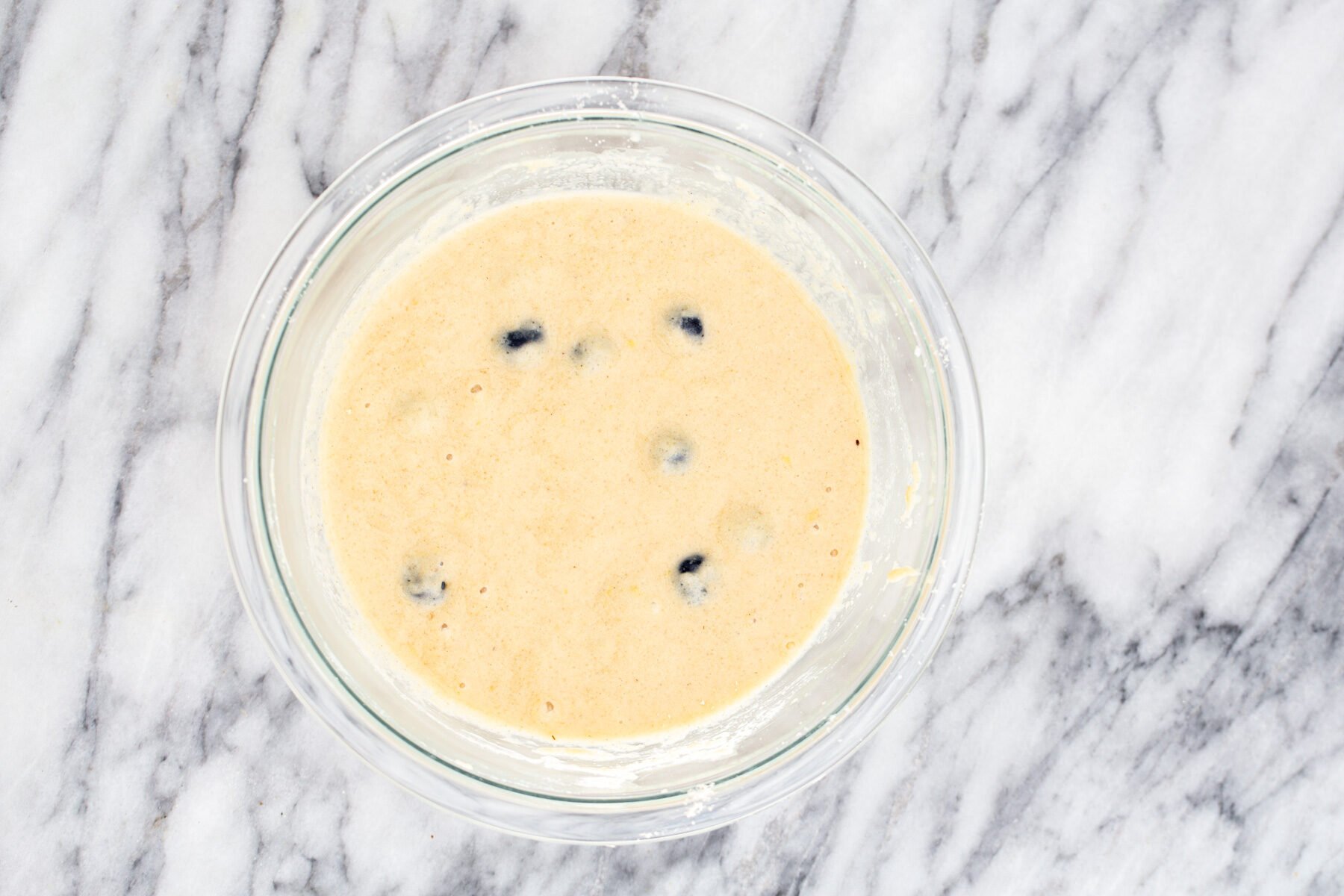 lemon blueberry waffles  a glass bowl with glutenfree waffle batter with blueberries and lemon zest