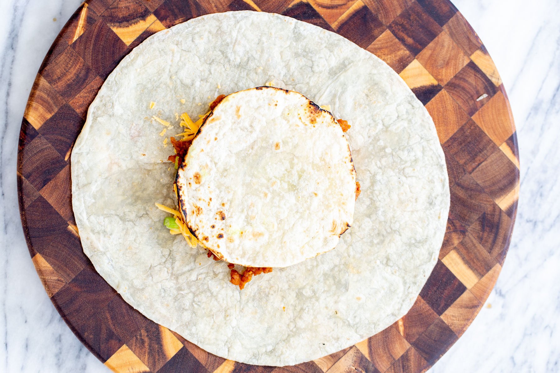 vegan crunchwrap  a tostada being placed on toppings