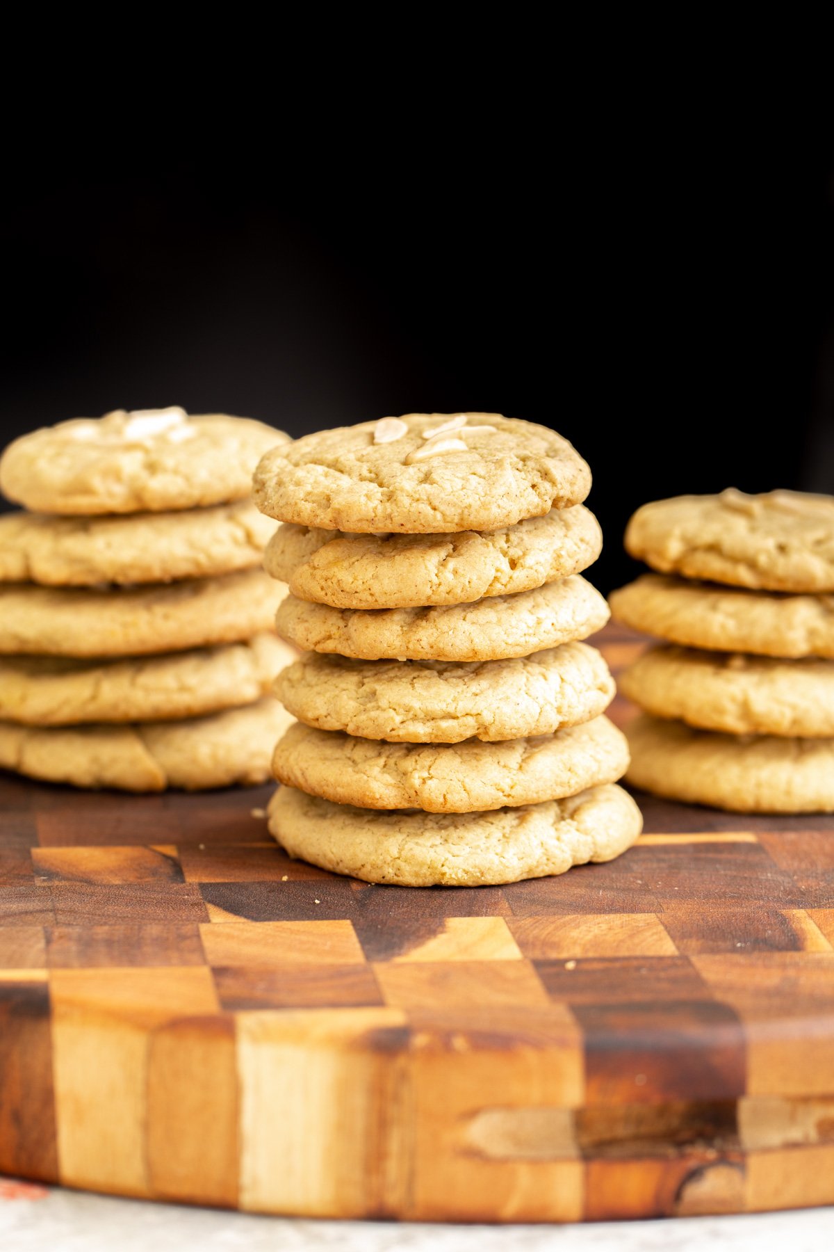 pistachio cookies stacked vegan almond flour pistachio cookies topped with slivered almonds on a wooden chopping board