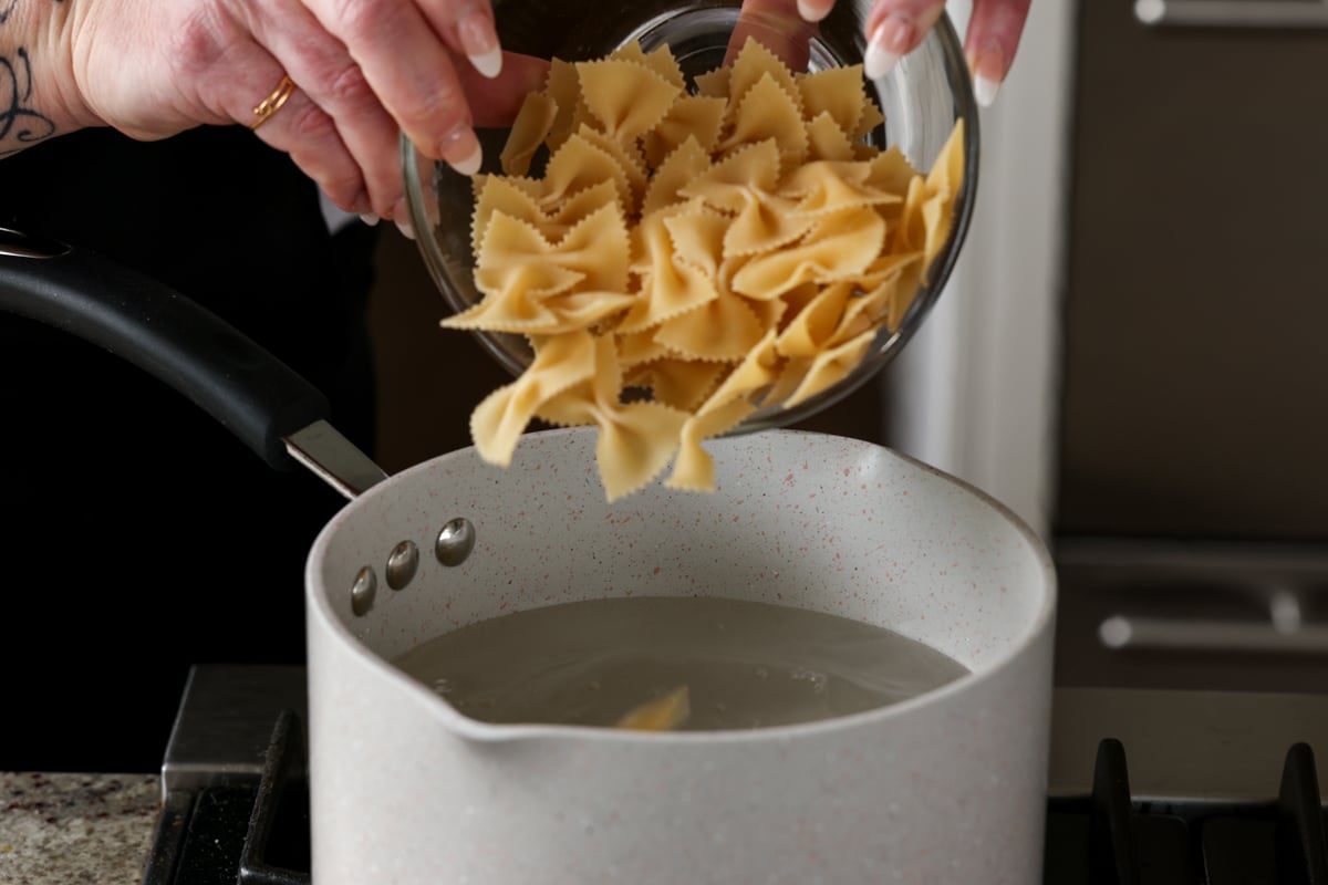 adding pasta to the pot of boiling water