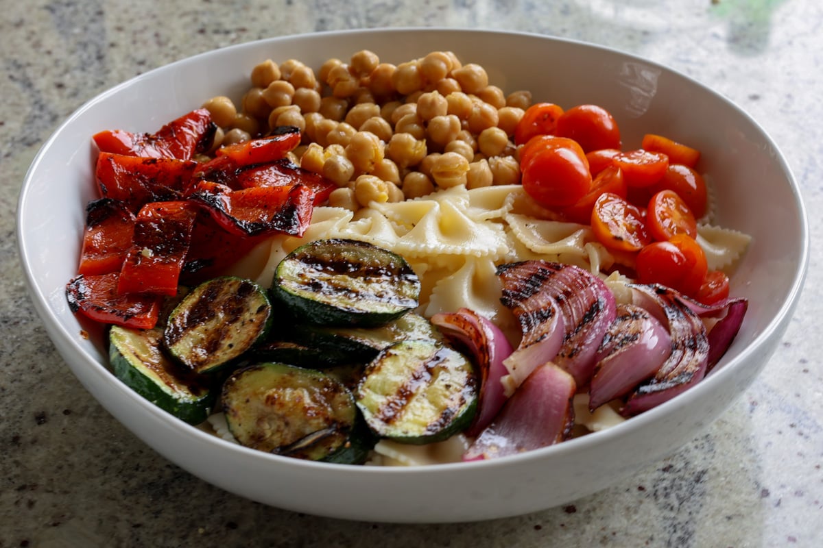 chickpeas, pasta, and grilled vegetables in the mixing bowl before mixing