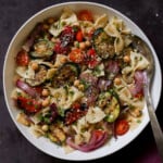 serving bowl of summer pasta salad with grilled vegetables with a spoon in it