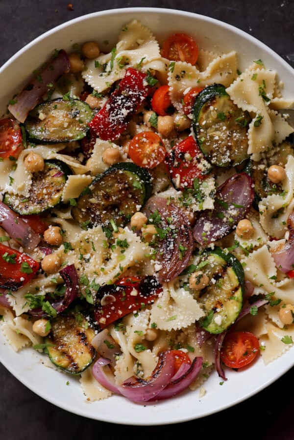 serving bowl of summer pasta salad with grilled vegetables with a spoon in it