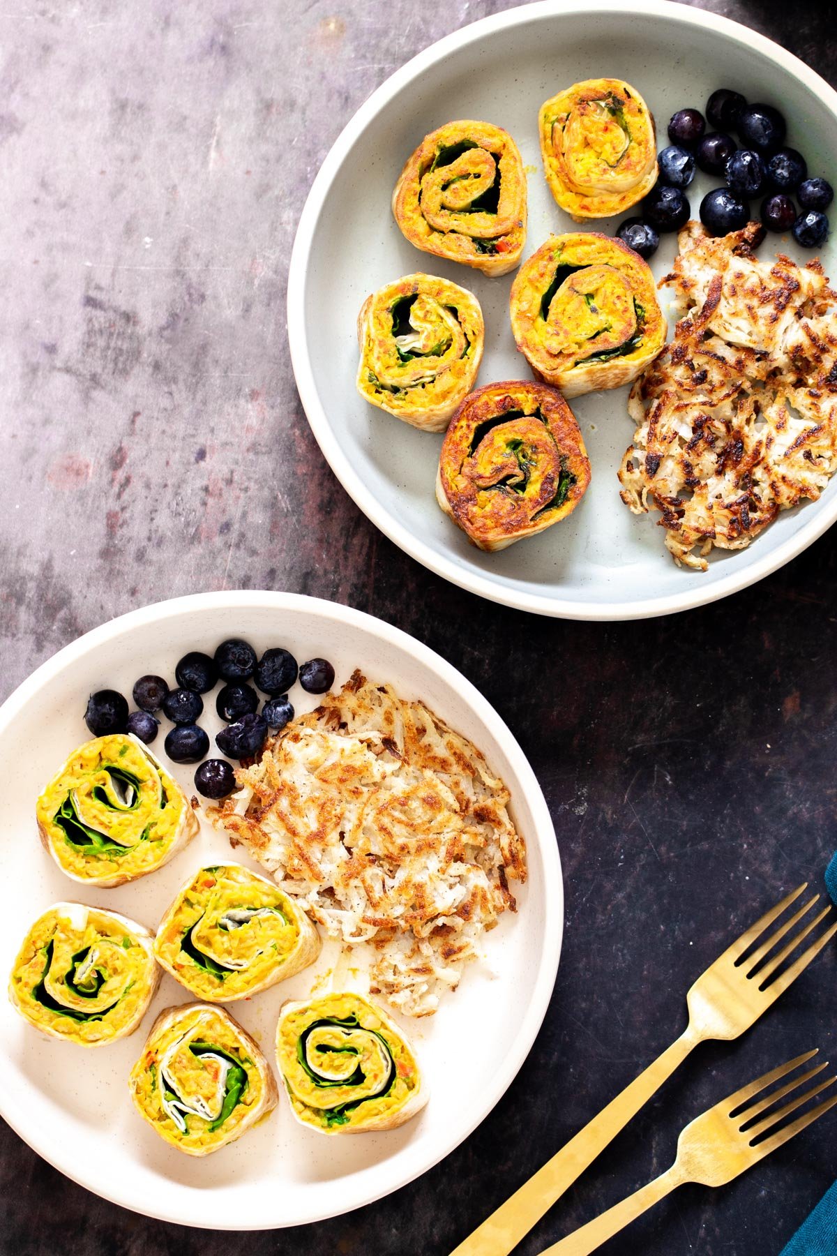chickpea breakfast  two plates with vegan chickpea breakfast scramble pinwheels served with berries and hashbrowns