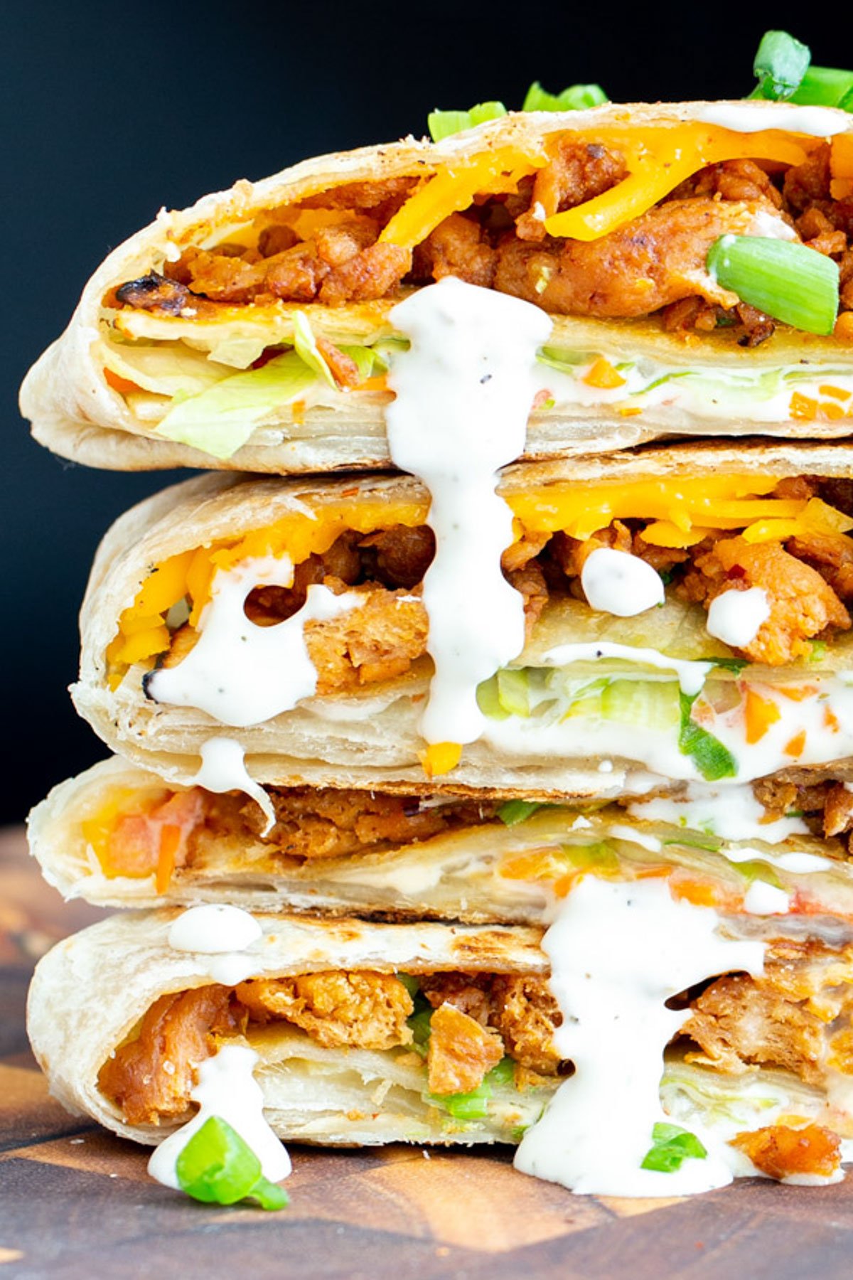 a stack of 3 halved vegan crunchwraps drizzled with vegan Ranch