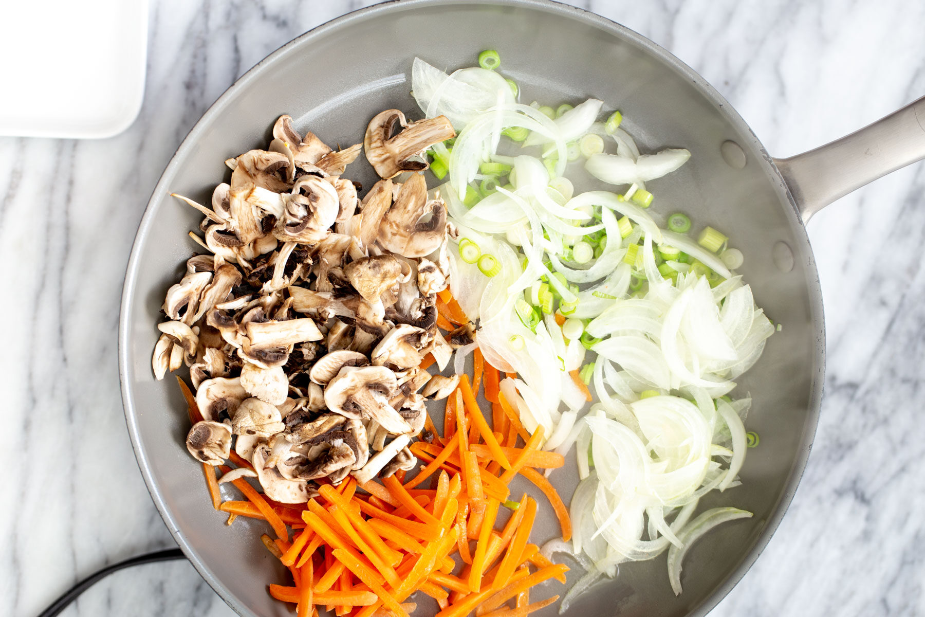 gochujang noodles sliced onions, carrots, mushrooms and spring onions in a saucepan