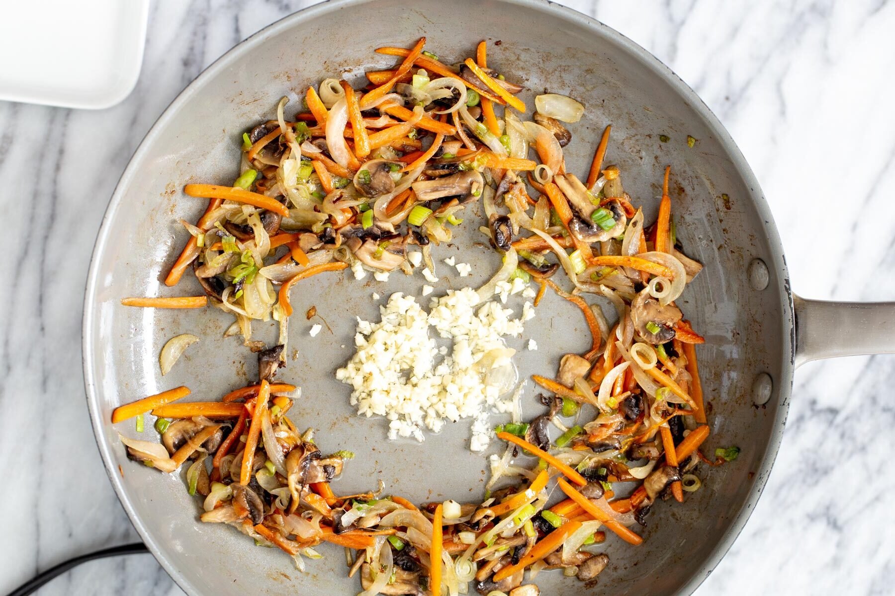 gochujang noodles  finely sliced veggies stir-frying with garlic in a saucepan