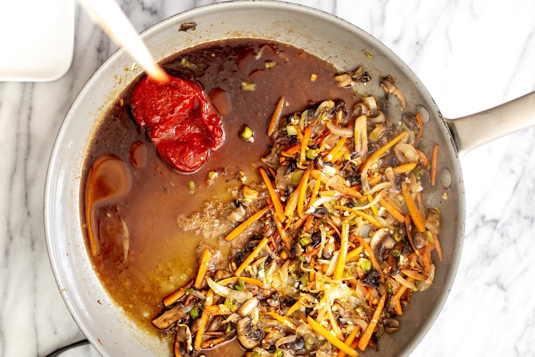 gochujang noodles  sauce ingredients for gochujang sauce being added to sauteed veggies in a saucepan