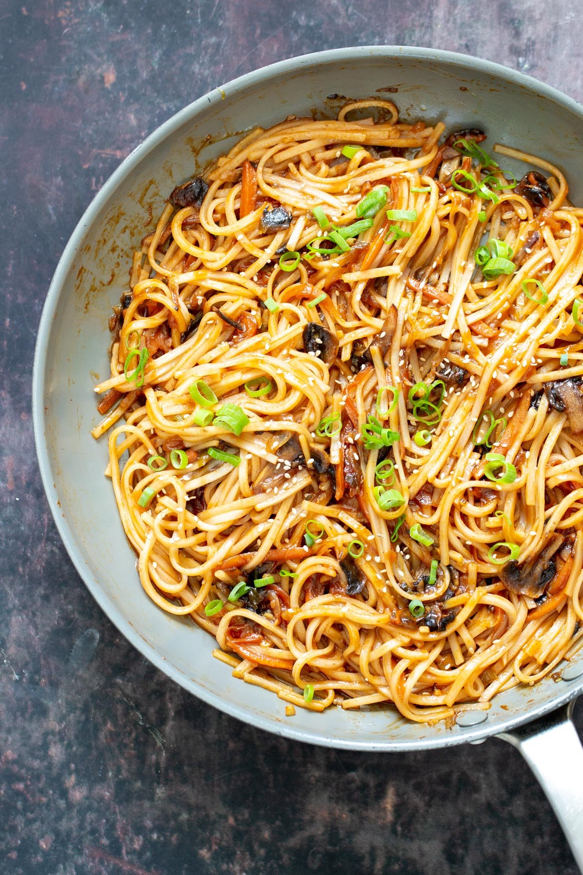 gochujang noodles a saucepan with gochujang noodles with mushrooms and sliced spring onions