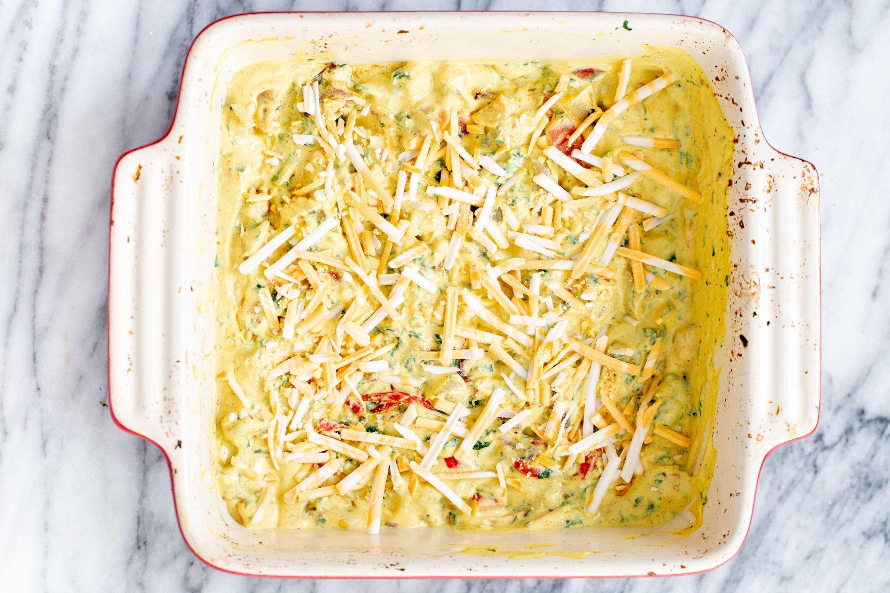 vegan egg breakfast casserole being topped with shredded cheese