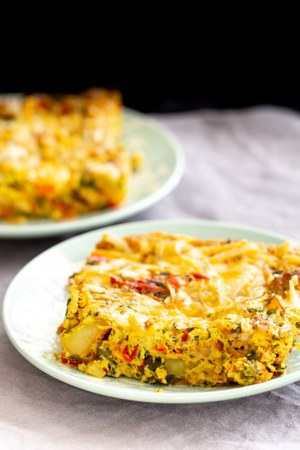 vegan Mexican casserole two plates with vegan Mexican egg breakfast casserole with bell pepper, potatoes and onions