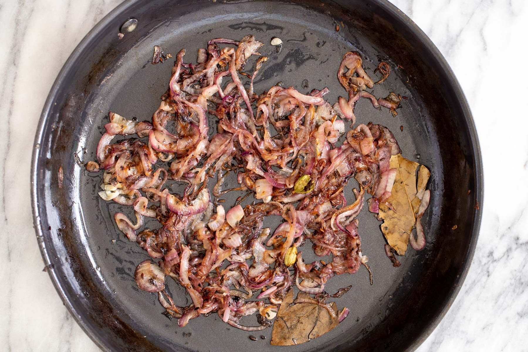 fried onions and spices in a black sauteeing pan