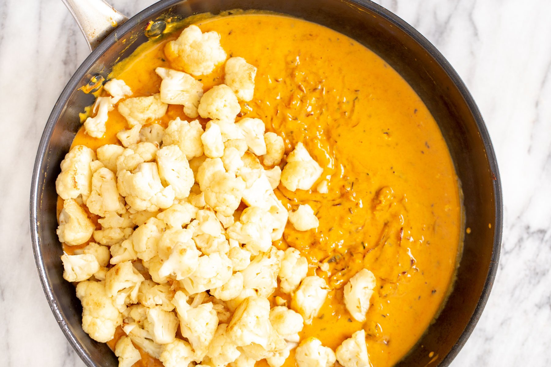 cauliflower florets in onion gravy in a saucepan