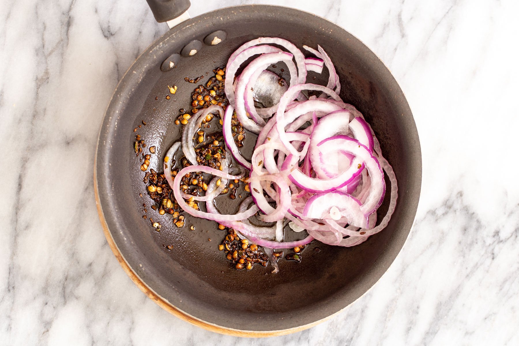 whole spices and onions in a frying pan