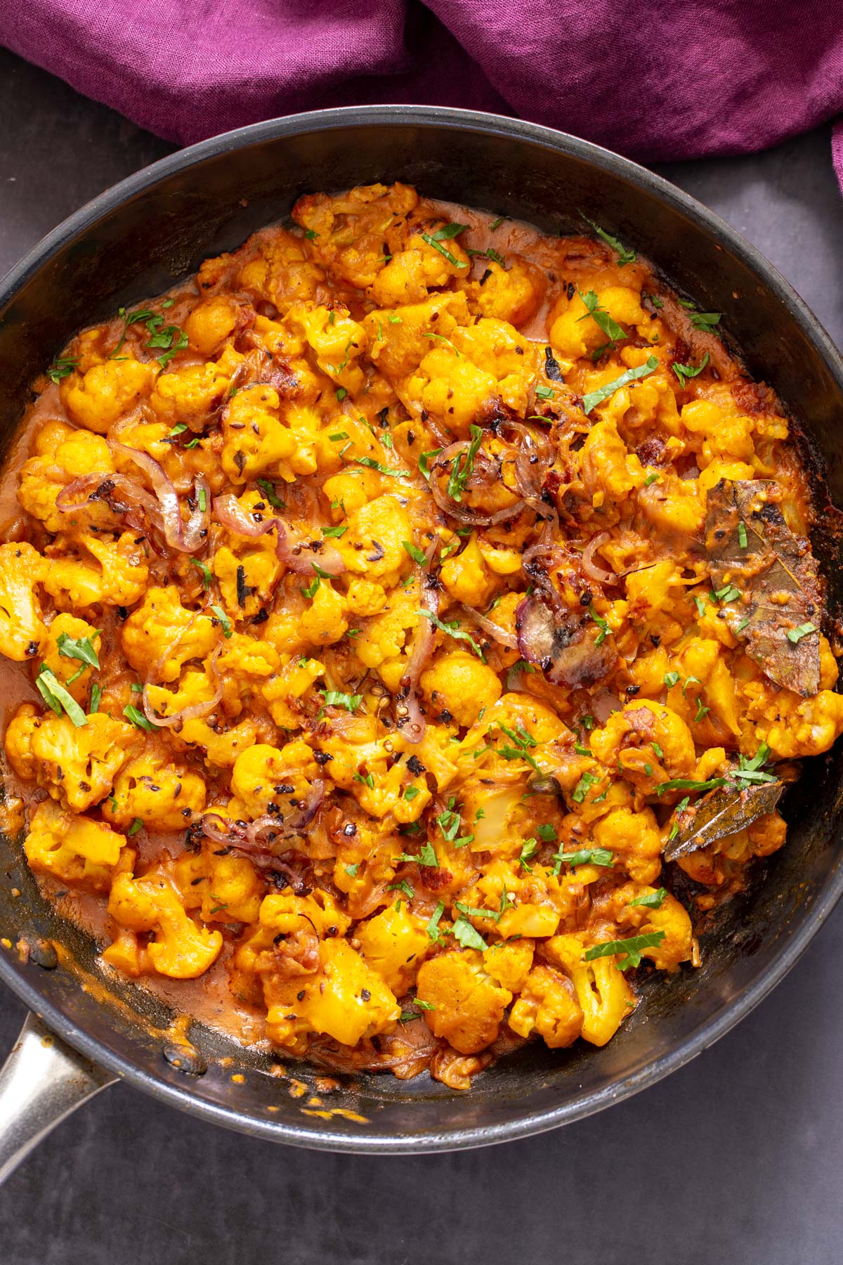 gobi do pyaza in a black sauteeing pan sprinkled with chopped cilantro