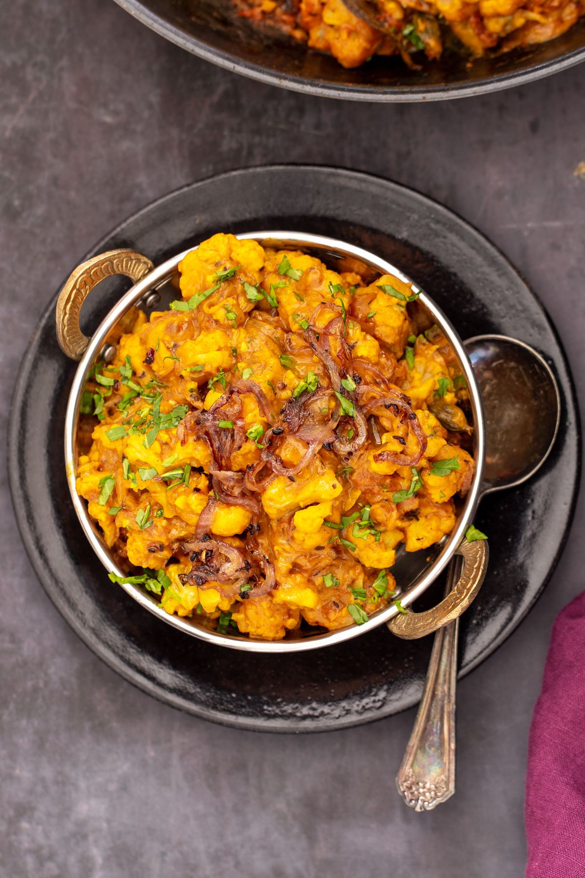 gobi Do Pyaza glutenfree Indian gobi do pyaza served in an Indian dish with a spoon on the side