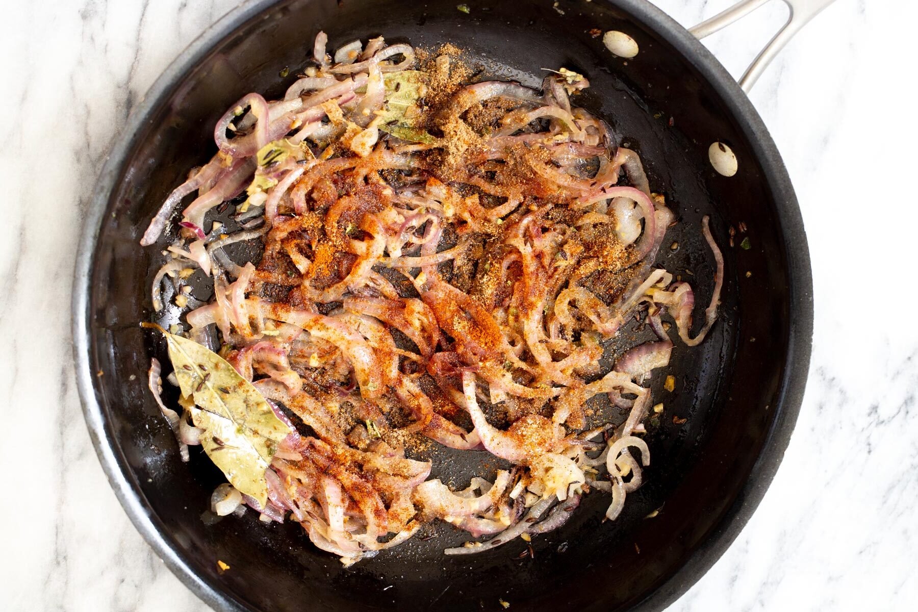 spices being added to sauteed onion