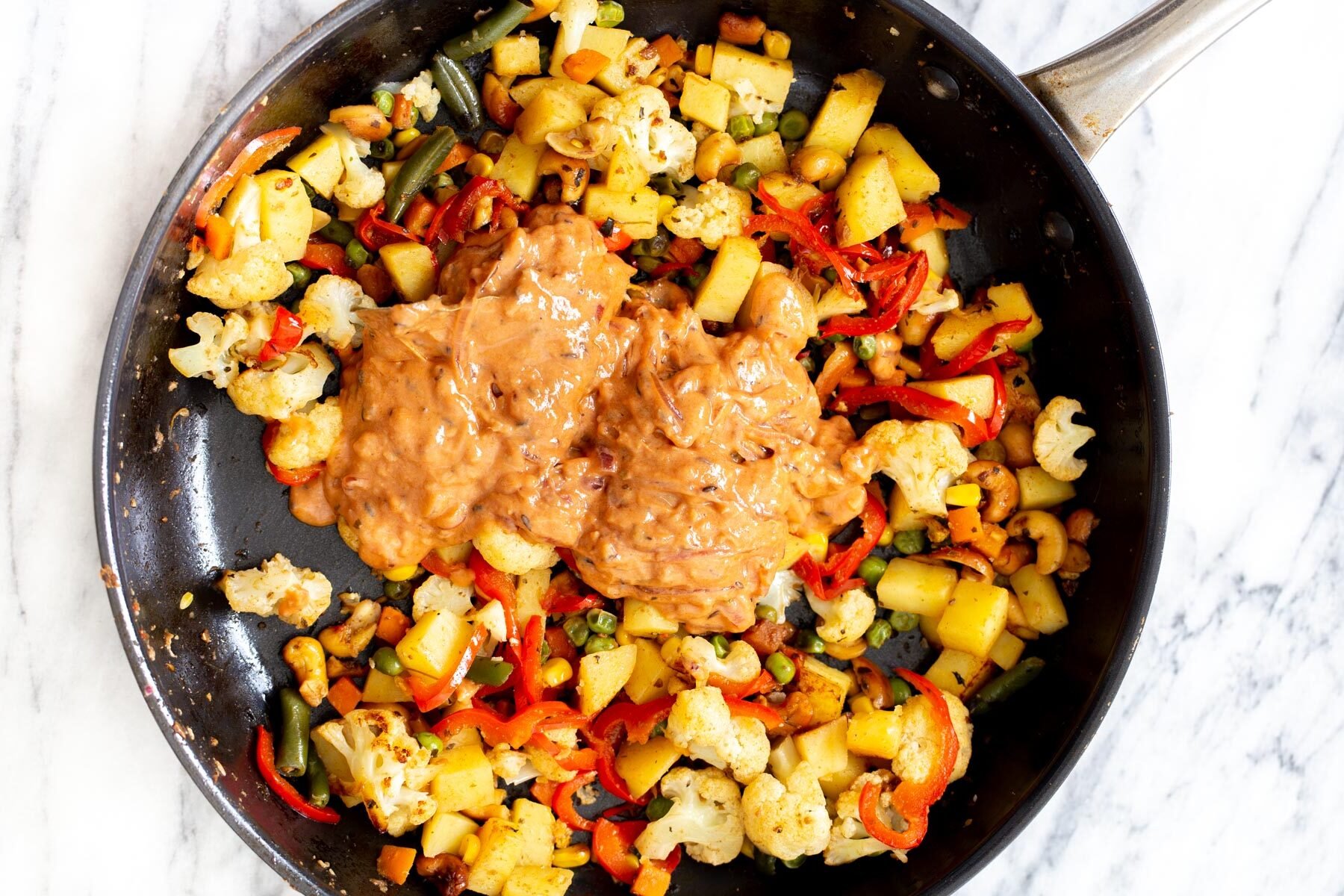 creamy gravy being added to vegetables in a frying pan