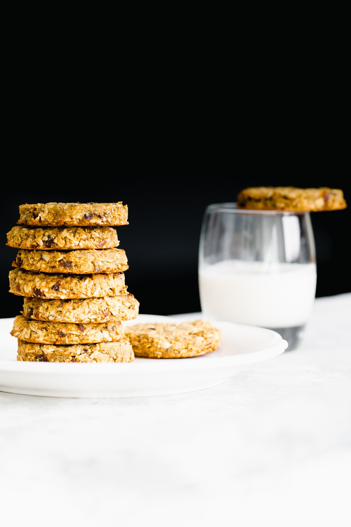 pumpkin breakfast cookies  stacked pumpkin breakfast cookies on a white plate with a glass of milk in the background