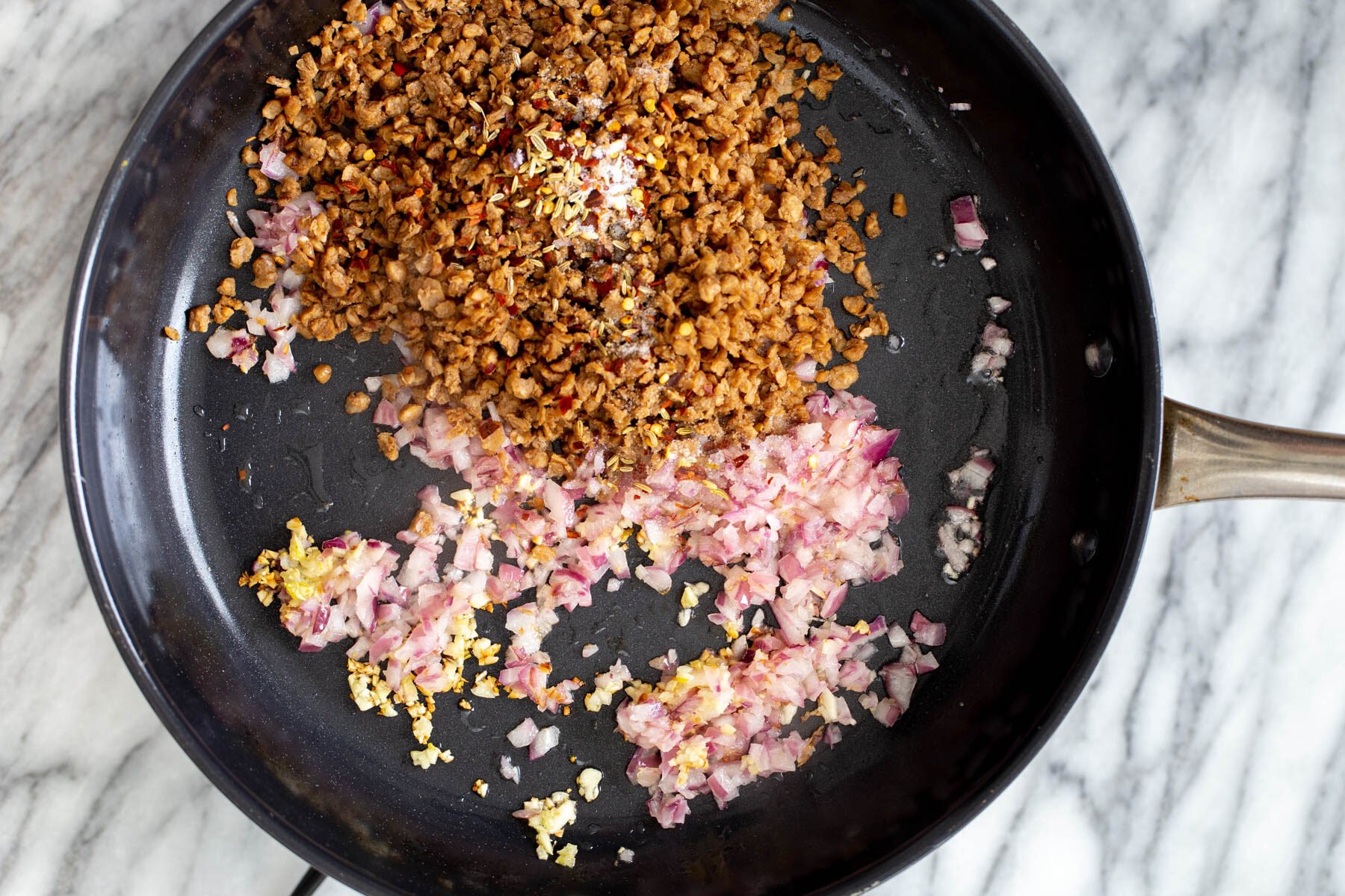 veggie crumbles being added to sauteed garlic and onions