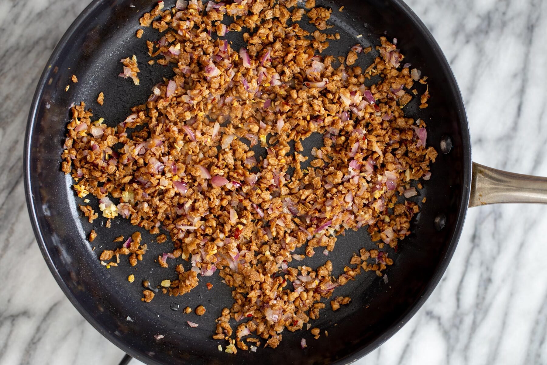 veggie crumbles, sauteed onions and garlic in a black skillet