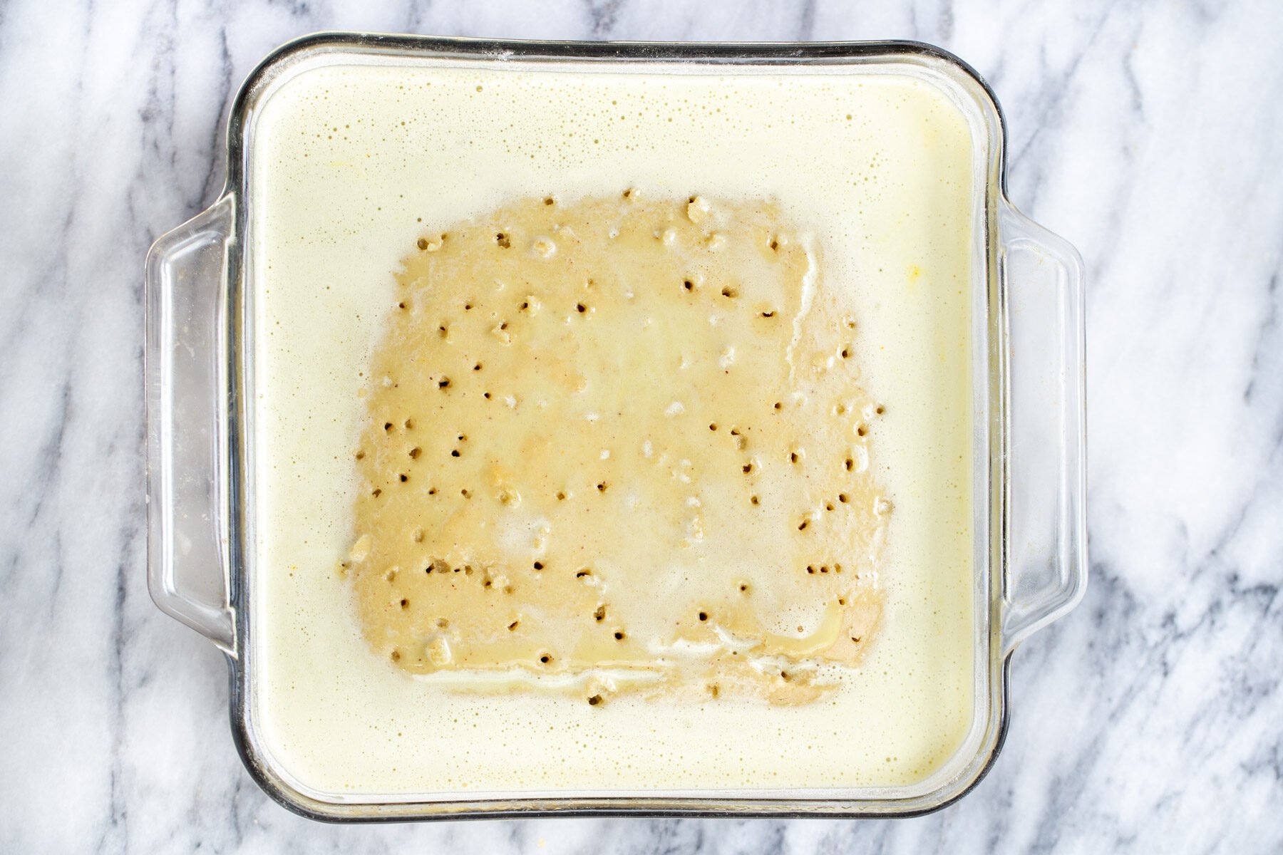 nut milk being poured over sponge cake to make vegan tres leches