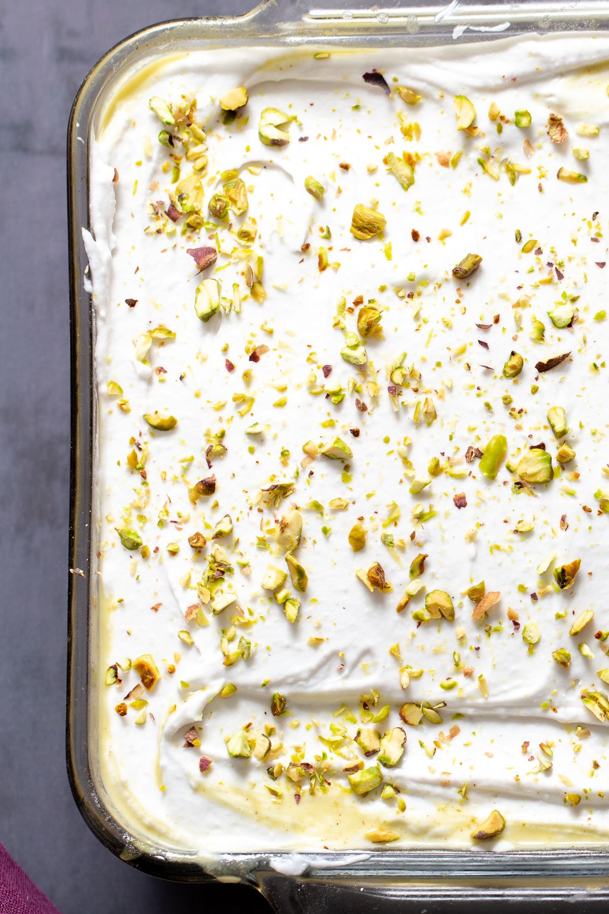 overhead shot of vegan ras malai tres leches cake sprinkled with pistachios