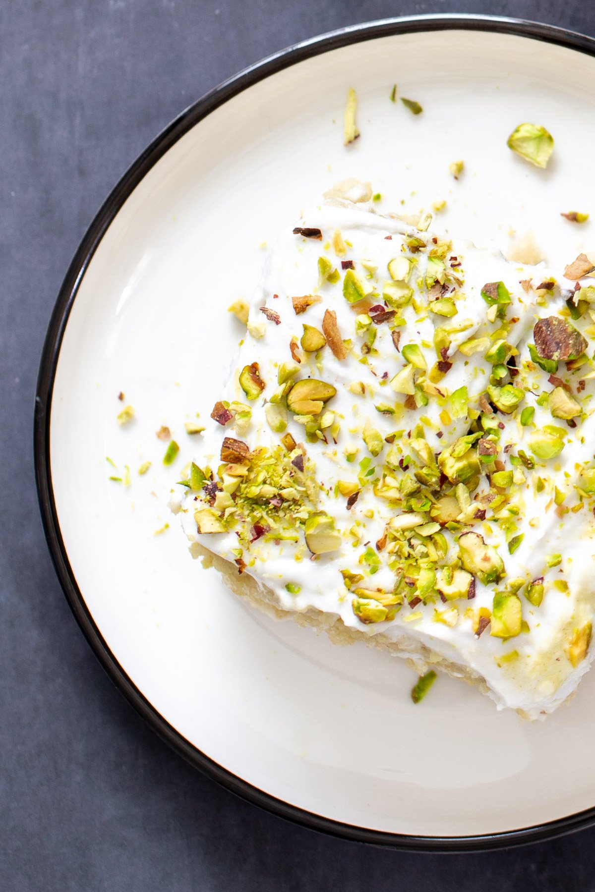 vegan tres leches  a slice of vegan ras malai tres leches sprinkled with pistachios served on a white plate