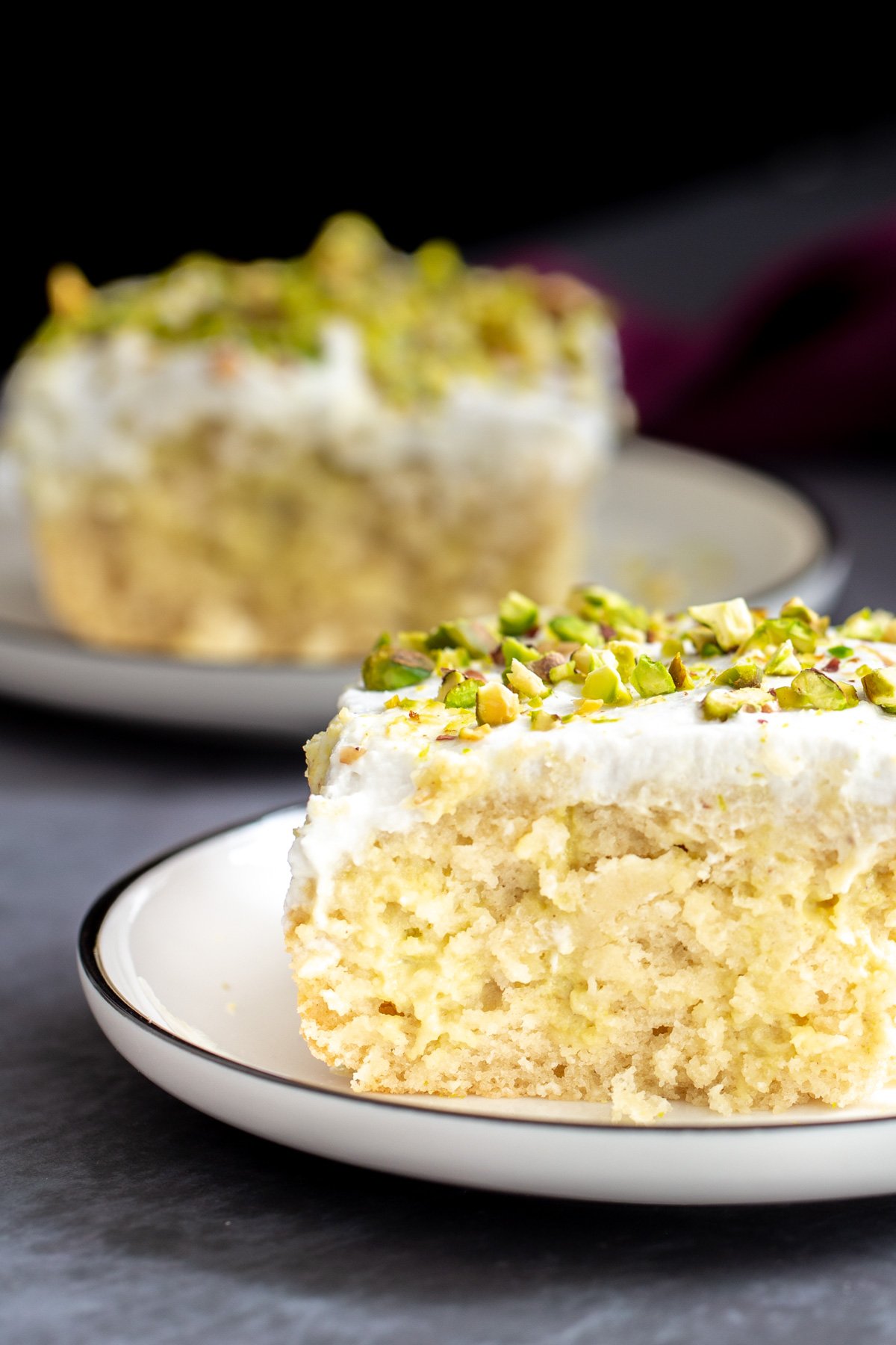 vegan tres leches  side view of a slice of vegan tres leches cake sprinkled with pistachios