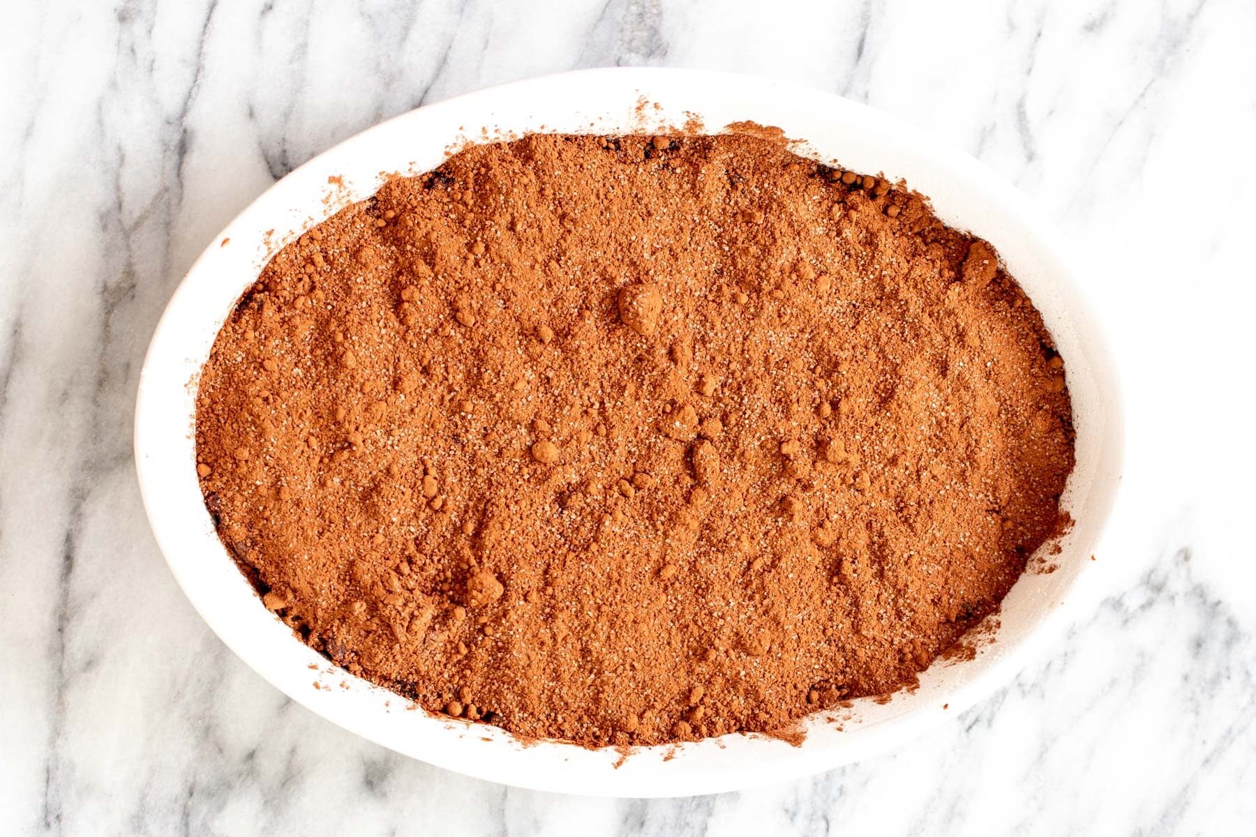 vegan self saucing pudding cocoa and sugar sprinkled on top of chocolate batter