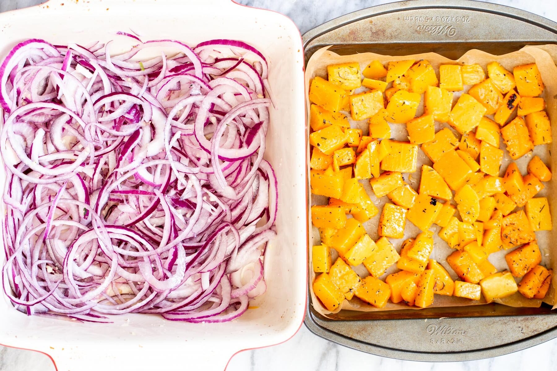 red onions and butternut squash cubes in two roasting pans