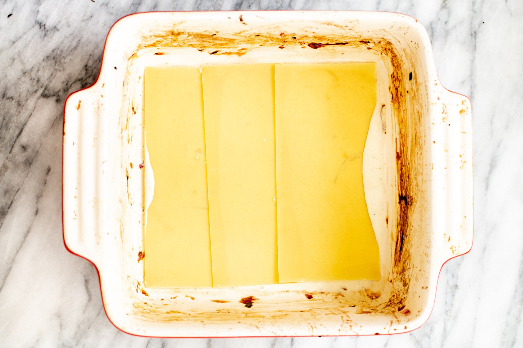 lasagna noodles being added to casserole dish