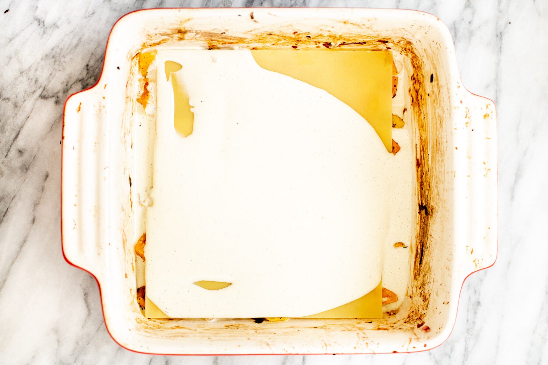 vegan bechamel sauce being added on top of lasagna pasta