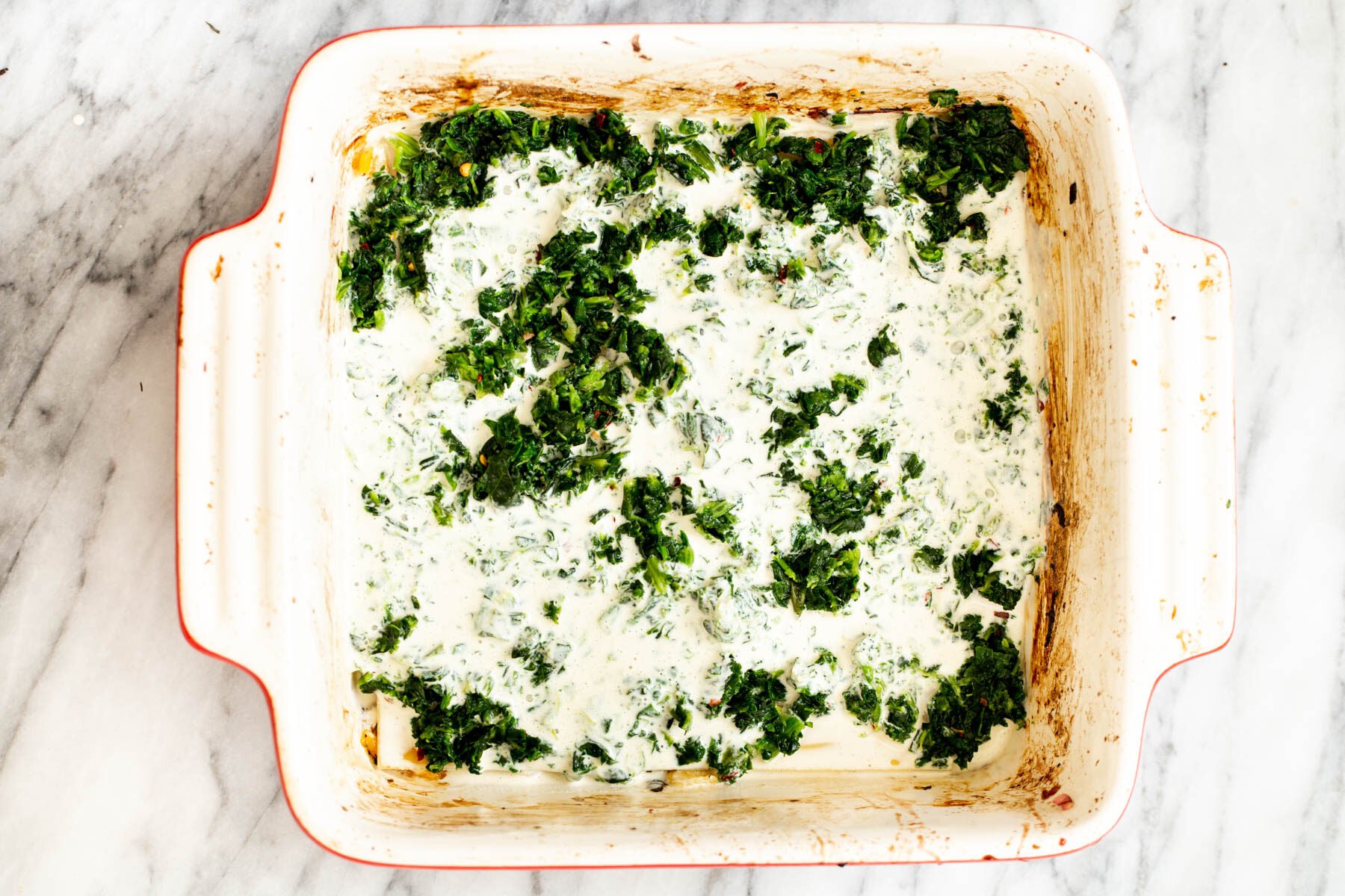 bechamel sauce being added to lasagna dish to make butternut squash lasagna