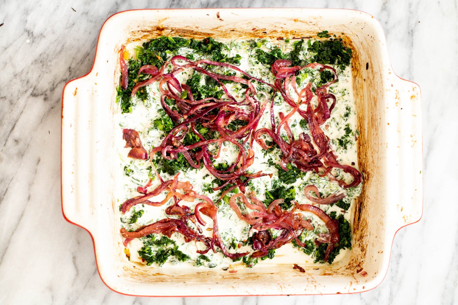 caramelized onion being added on top of spinach and bechamel
