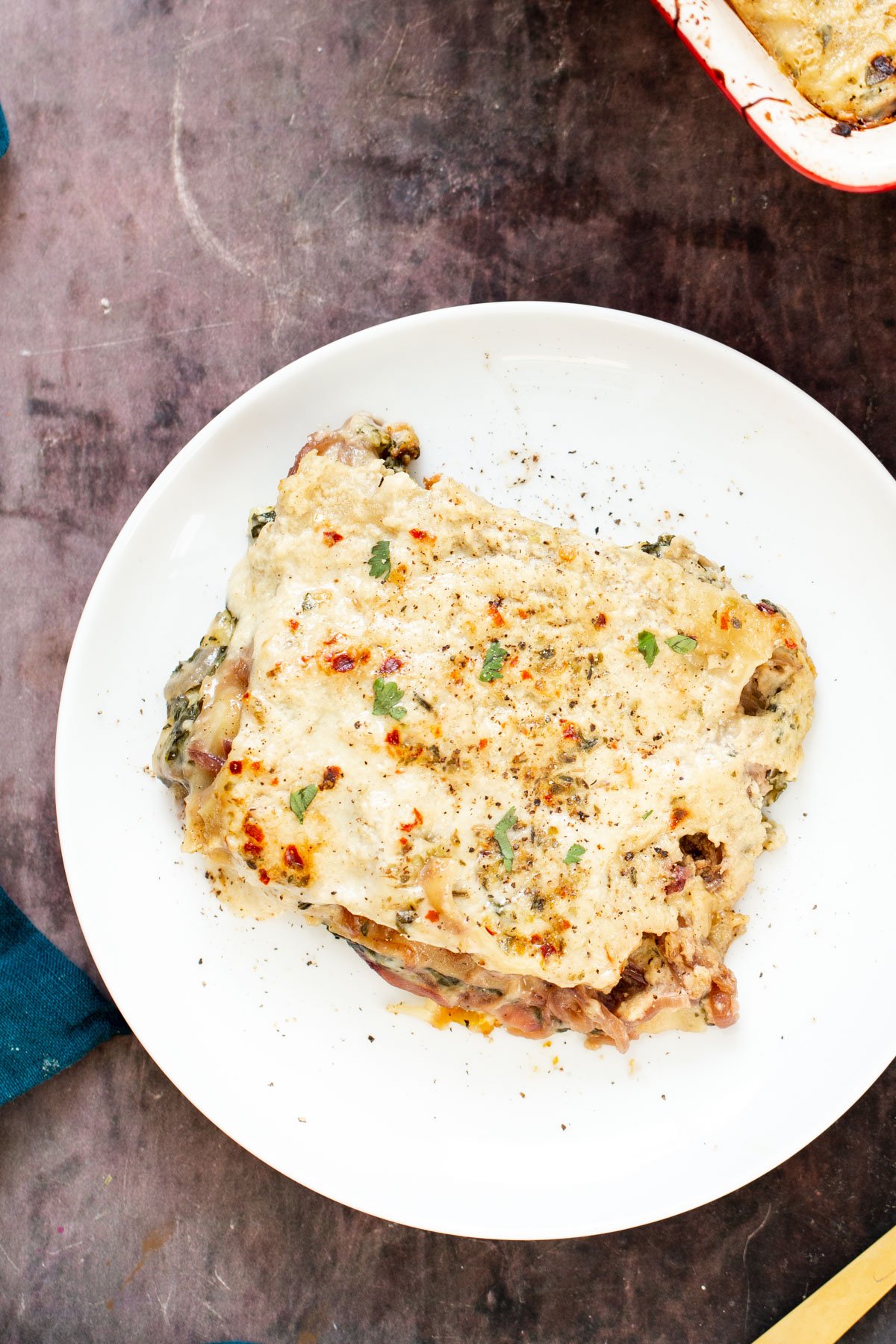 a serving of vegan butternut squash lasagna with spinach and caramelized onions on a white plate