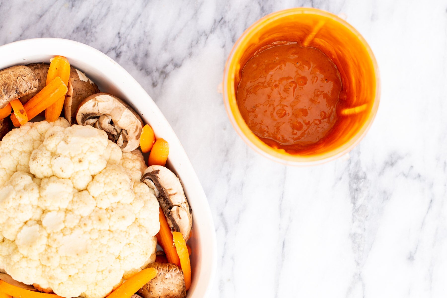 whole roasted cauliflower vegan cauliflower and asian peanut butter miso glaze on a white marble countertop