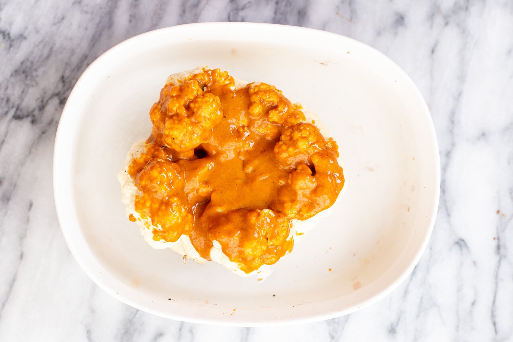 whole roasted cauliflower vegan vegan whole roasted cauliflower in a white casserole dish