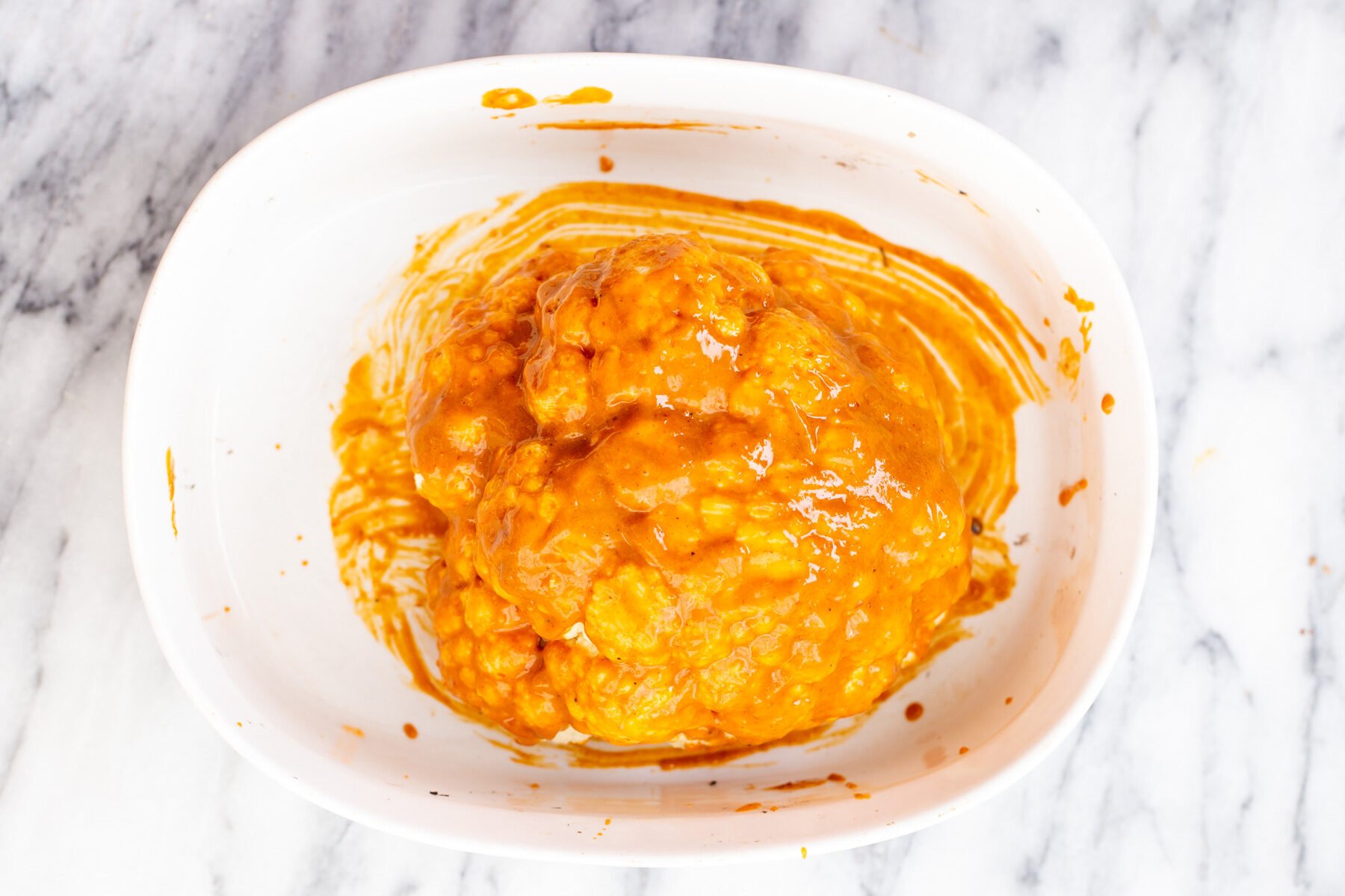 whole roasted cauliflower vegan a miso peanut butter glazed head of cauliflower in a white casserole dish