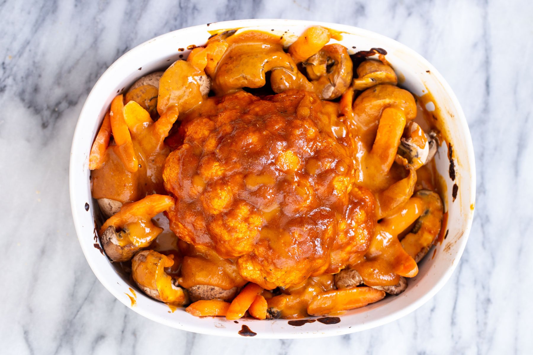 cauliflower head glazed with miso peanut butter mixture ready for baking