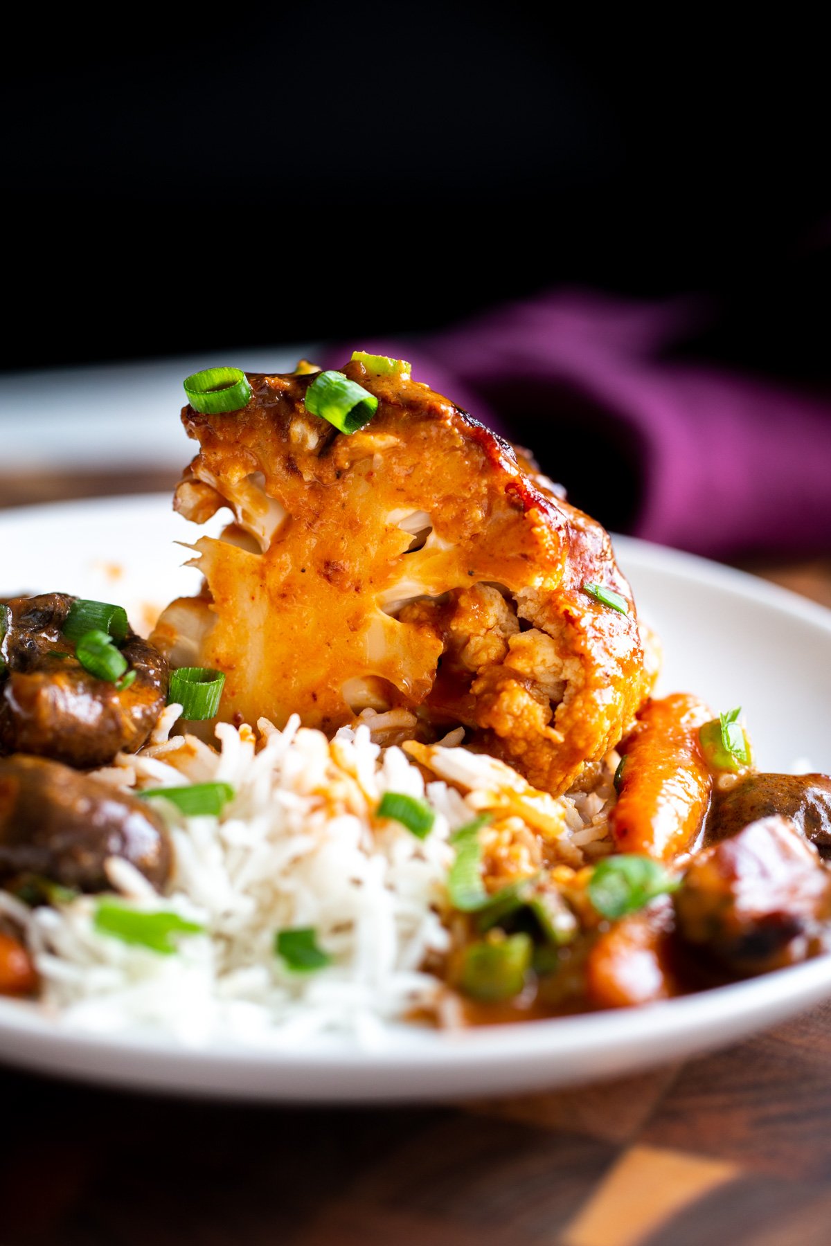 a wedge of baked whole peanut butter miso roasted cauliflower with a side of rice