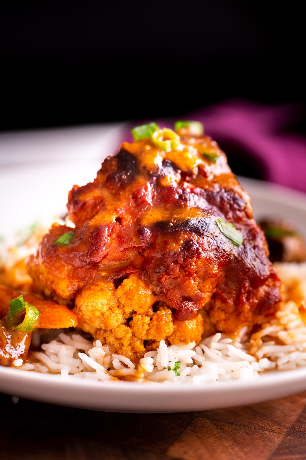 miso roasted cauliflower side view of an Asian glazed whole roasted cauliflower with miso peanut butter glaze