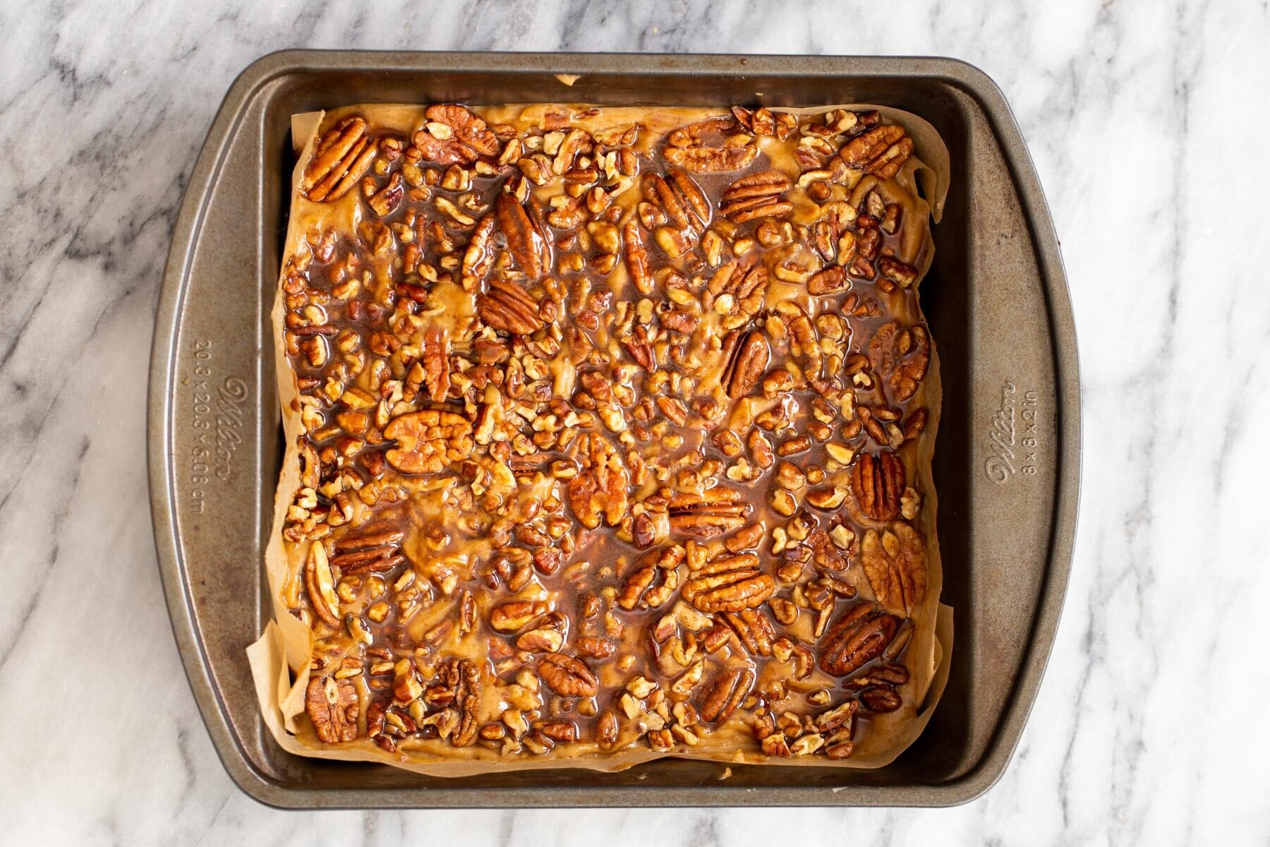vegan pecan pie bars  shortcrust pastry topped with pecans and maple syrup