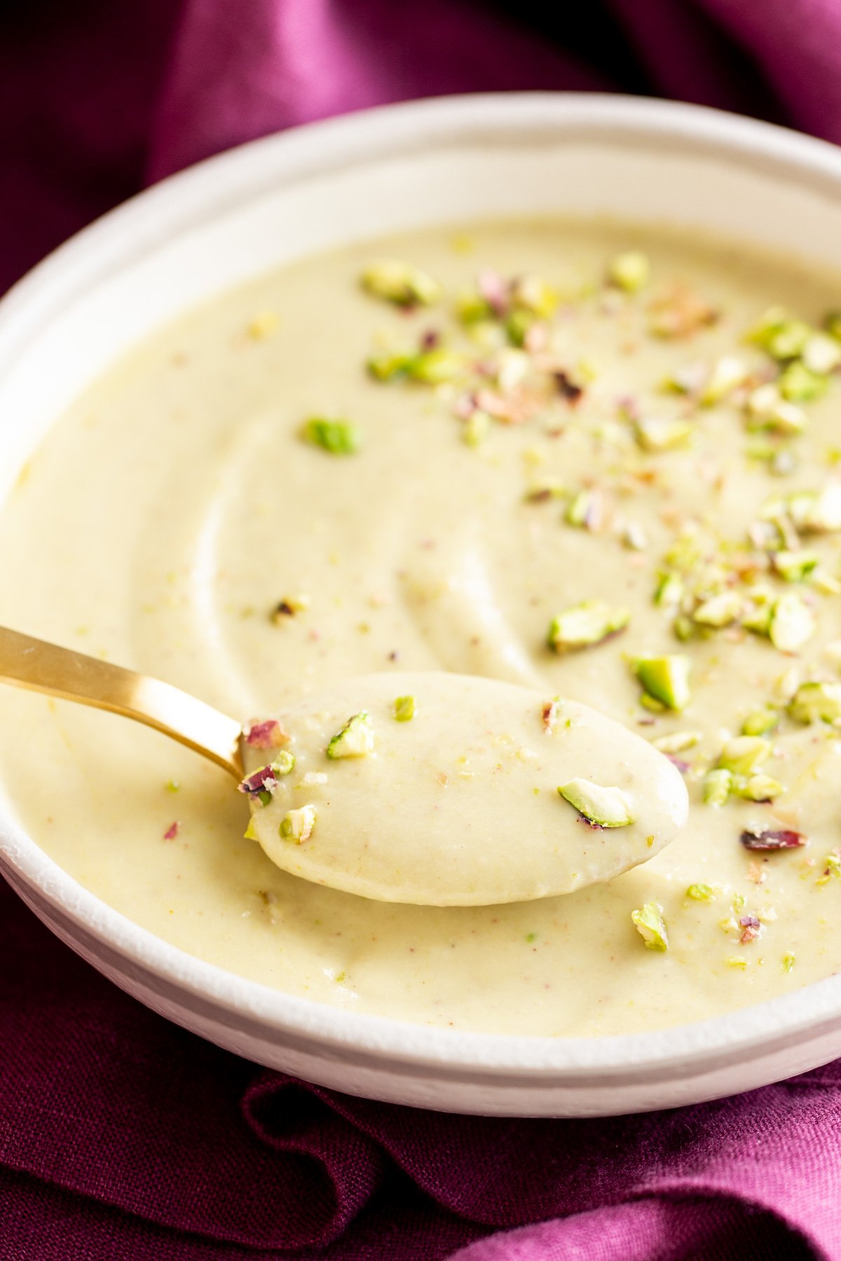 rabri recipe a spoon being dipped in a bowl with vegan pudding rabri