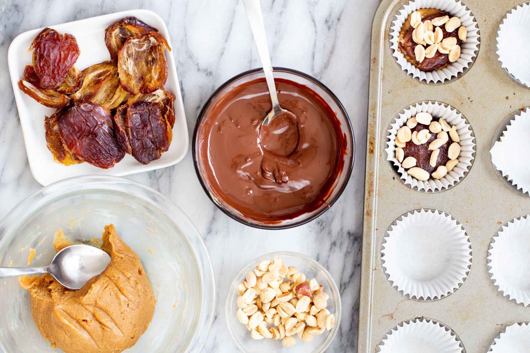 peanuts being added to peanut nougat filled chocolate cups to make vegan snickers cups
